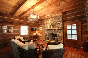 Living area, fireplace, couch, heavy beams, authentic cabin.