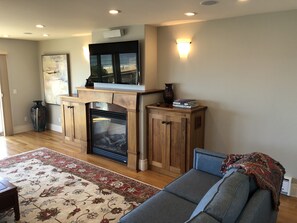 Hardwood decorated gas fireplace sits beneath 55 inch televison in living room.