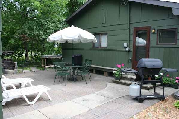 Cozy patio with fire pit, grill, umbrella table, loungers, fish cleaning table.