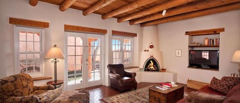 Spacious living area has kiva fireplace, grand Vigas, and Santa Fe blue sky