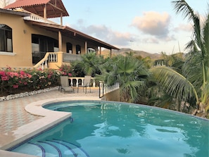 View of the veranda from the pool with hills in the background