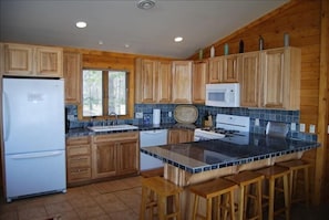 Kitchen bar area, open floor plan to living room, dining room. Fully stocked.