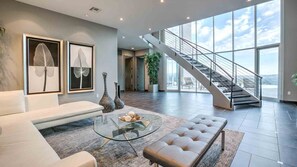 Main floor formal seating area w/ grand staircase, natural lighting, & views