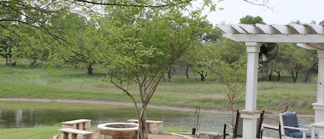 Peaceful setting beside house and pond. Firepit and covered pergola and sink.