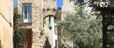 La Place et notre maison à gauche avec les volets bleus et les marches