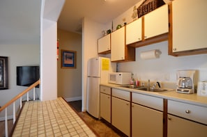 Galley kitchen with ceramic tile floor and open pass through to dining area