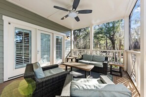The screened porch has a seating area. The perfect spot for afternoon cocktails and to watch the horses saunter along the horse trail.