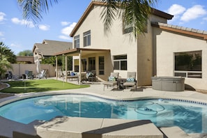 Beautiful backyard with pool, pool loungers, seating area, putting green, hot tub