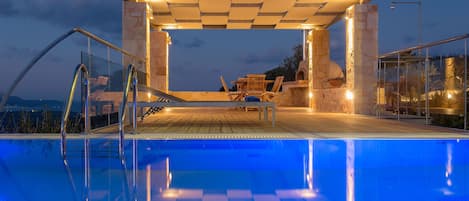 Pool terrace features outdoor shower, shaded dining area with a wood stove