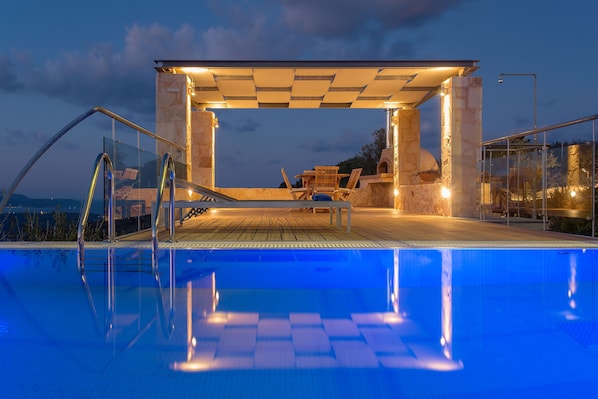 Pool terrace features outdoor shower, shaded dining area with a wood stove