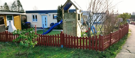 Blick auf den Spielturm mit Innensandkasten, Rutsche und Schaukel
