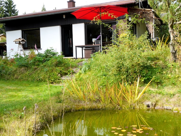 Ferienhaus Frontansicht mit Teich und Sonnenterrasse