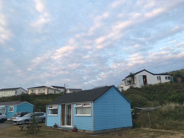 The chalet from the front with picnic bench, raised grassy area, washing line ..
