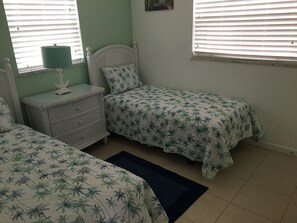 Twin beds in bedroom with nightstand, dresser and TV