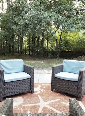 Outdoor patio set with table surrounding by lush green trees.