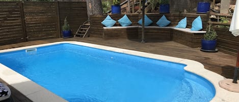 Decked pool area with sun loungers and seating. 