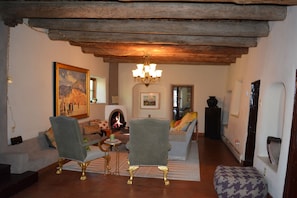 Large living room with traditional viga ceilings and wood burning kiva fireplace