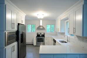 Modern kitchen w/all white cabinetry, white quartz countertops, & slate floor