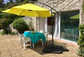 Front of groundfloor and entrance with large table, chairs and parasol 