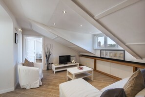 Living room with sofa bed and TV. In the background the first bedroom