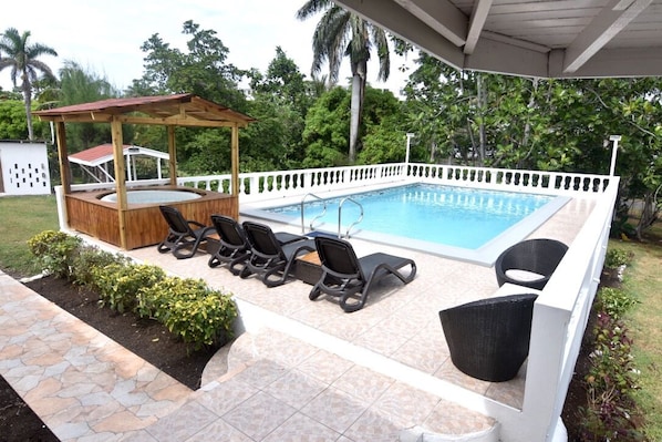Swimming pool with Jacuzzi also pool furniture with BBQ pit roof to the left