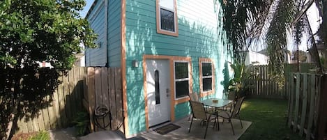 Patio with table, chairs, shade umbrella, grill and hose to rinse off the sand 