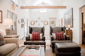 Living room with vaulted ceilings, shiplap, wood burning fireplace, and comfy seating.