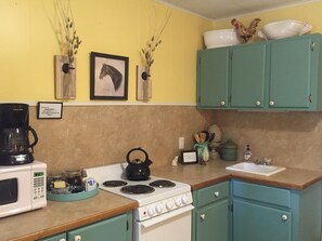 Kitchen stocked with fridge, microwave, coffee pot, stove, utensils, dishes, etc