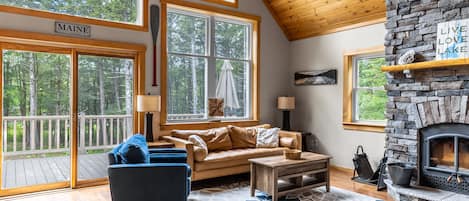 Living room with floor to ceiling stone fireplace (wood not provided). Comfortable leather couch, Roku TV, fast Starlink WIFI, huge windows overlooking the lake.