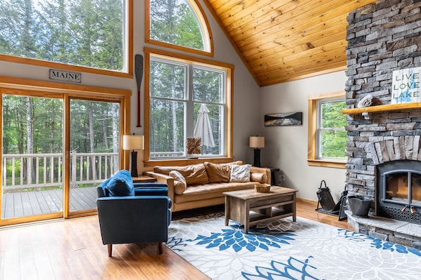 Living room with floor to ceiling stone fireplace (wood not provided). Comfortable leather couch, Roku TV, fast Starlink WIFI, huge windows overlooking the lake.