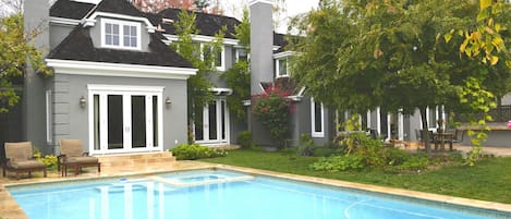 Backyard swimming pool surrounded by lush green trees.