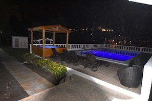 Stunning night shot of swimming pool with spa Jacuzzi in the background