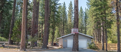 Front of the property featuring large driveway and basketball hoop