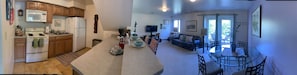Pano of the fully stocked kitchen, living and dining room overlooking the patio.