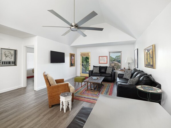 Large comfortable furnishings, excellent modern décor and TV. This view shows the door to the balcony and abundance of natural light.