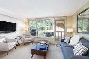 Living room with flat screen tv, chairs, and couch.