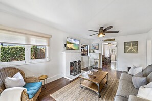 Light and windows surround this cozy, comfortable living room with fireplace. 