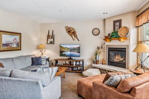 Living Room: L-shaped couch, plush armchair, TV, gas fireplace