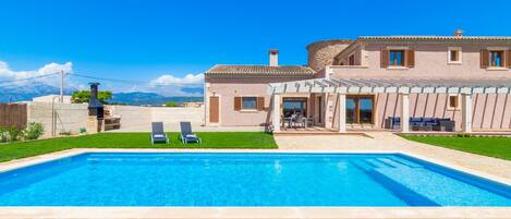 Large pool and terrace surrounded by natural grass