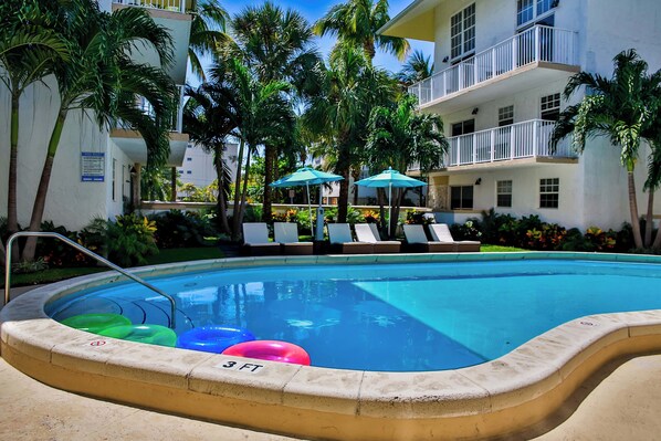 Large swimming pool with poolside loungers and umbrellas