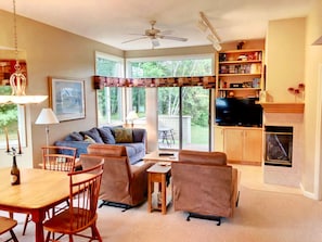 The living/dining area is cozy and sunny open concept space with dining table that seats 4 and comfortable furniture that surrounds the gas fireplace.