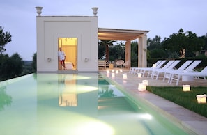 the pool at dusk with pool bedroom and portico