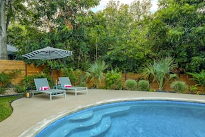 The sparkling pool is surrounded by lush landscaping