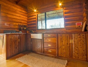 Wooden hand-made kitchen with butler sink, utensils and stove top.