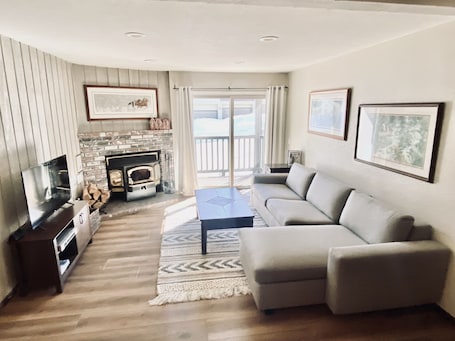 Cozy living room with luxury sofa + sleeper, wood burning fireplace & TV