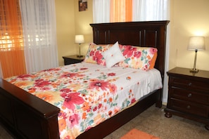 Refresh in our bright floral queen bedroom with two bedside tables and lamps.