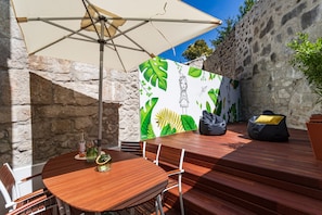 Patio with table, chairs, sun umbrella, bean bag, and wall painted by Costah.