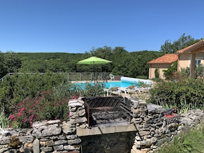 Barbecue en pierre avec vue sur la piscine et la terrasse