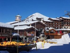 Vue de l'appartement en hiver : restaurants, magasins, télécabine, piste et luge