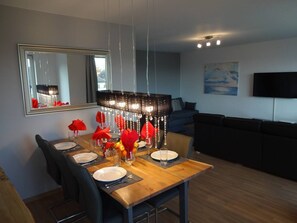 Der Esstisch in dem großen Wohnraum sitzt 6 Leute.
